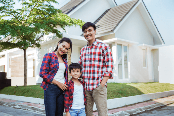Happy family standing in front of their new home after successfully buying a home in San Diego with VA loan or first-time buyer assistance
